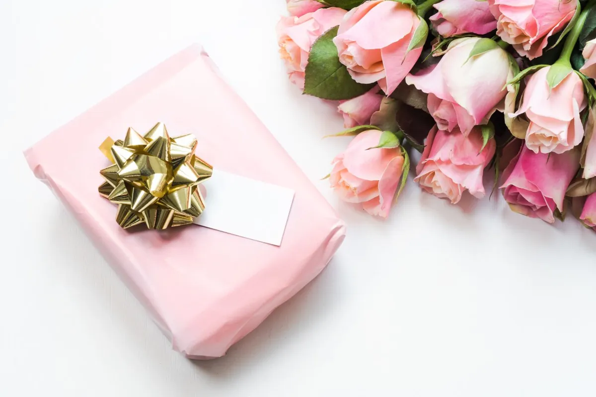 Pink gift box with a gold bow and roses